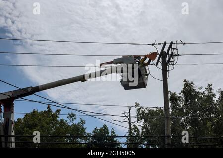 Elektriker reparieren Draht der Stromleitung am Strommast nach Hurrikan Stockfoto