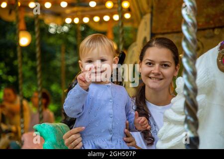 Nettes Baby Mädchen mit Mutter auf dem Pferd von alten Retro-Karussell, Prag, Tschechische republik Stockfoto