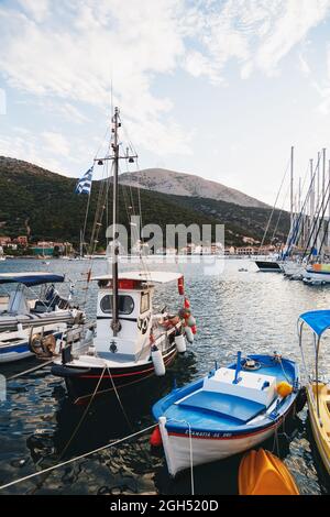 Agia Efimia, Insel Cefalonia, Griechenland - Juli 12 2019: Kleine Fischerboote und weiße Yachten ankern in einer Bucht der Insel Cefalonia, Griechenland Stockfoto