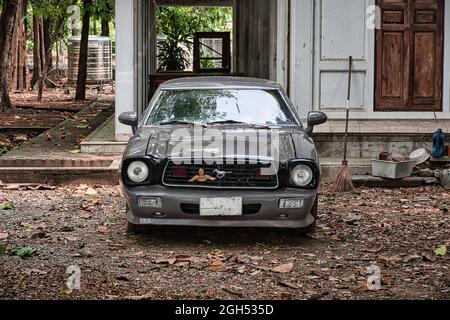 Bangkok, Thailand 04.07.2021 der alte Ford Mustang sitzt im Park neben dem Wat Nang Chi Chotikaram Tempel Stockfoto