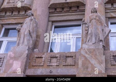 Zwei weibliche Granitstatuen mit Topf und Schwert an der Wand des Budapester Baues Stockfoto