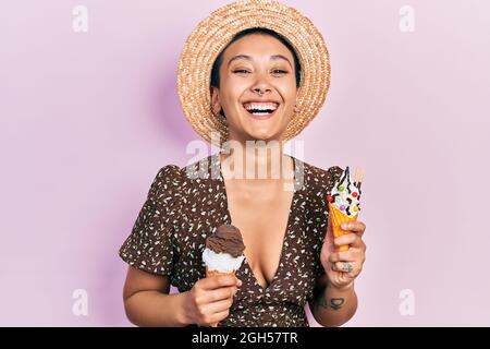 Schöne hispanische Frau mit kurzen Haaren, die Eiszapfen isst, lächelt und lacht laut, weil lustig verrückt Witz. Stockfoto