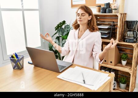 ¡Junge kaukasische Geschäftsfrau meditiert Yoga-Übungen im Büro. Stockfoto