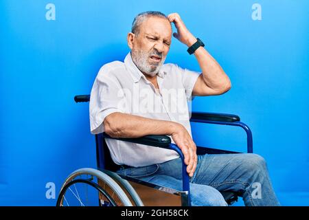 Schöner älterer Mann mit Bart auf Rollstuhl sitzen verwirrt und fragen sich über Frage. Unsicher mit Zweifel, Denken mit Hand auf Kopf. Nachdenklich c Stockfoto