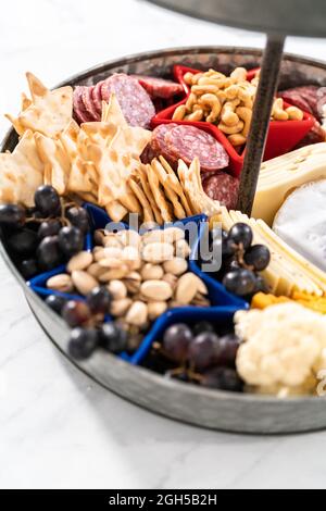 Am 4. Juli gab es ein Charcuterie-Brett auf einem zweistufigen Metallständer, gefüllt mit Käse, Crackern, Salami und frischem Obst Stockfoto