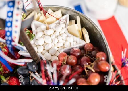 Am 4. Juli gab es ein Charcuterie-Brett auf einem zweistufigen Metallständer, gefüllt mit Käse, Crackern, Salami und frischem Obst Stockfoto