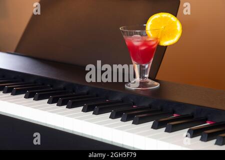 Strahlend roter Cocktail auf dem Klavier zur Happy Hour Stockfoto