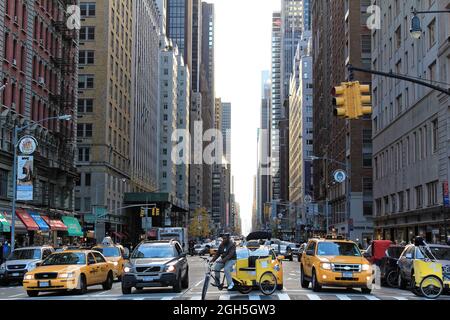 New York, USA - 21. November 2010: Die Menschen fahren gelbe Taxis entlang der 6th Avenue. In New York City waren 13,237 gelbe Taxis registriert. Stockfoto
