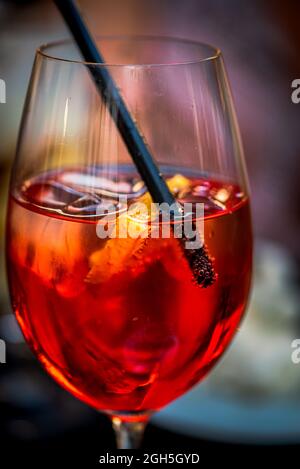 Frischer roter Cocktail mit Eiswürfeln und einem Strohhalm, Nahaufnahme eines leichten alkoholischen Getränks Stockfoto