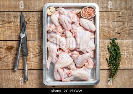 Rohe Hähnchenflügel Geflügelfleisch bereit zum Kochen mit Kräutern. Holzhintergrund. Draufsicht Stockfoto