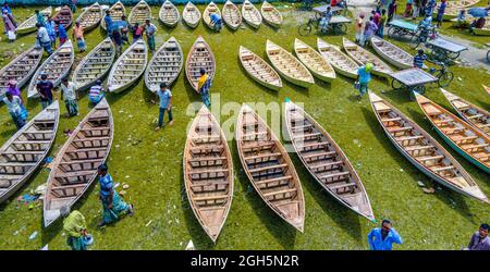 Luftaufnahme von Personen aus Savar und Aminbazar, die am Markt ankommen, um Boote zu kaufen, um sie in ländlichen Gebieten während der Monsunsaison zu benutzen, wenn starker Regen Dörfer und Straßen überflutet, der Preis der Boote ist von BDT 1,500 bis BDT 5,000 (nationale Währung) Je nach Größe und Qualität der verwendeten Materialien. Die Nachfrage nach Dingi und Khosa Nauka (Kleinboot) ist für den Transport von Menschen in hochwassergefährdeten Gebieten gestiegen. Der Markt ist bekannt für den Verkauf von handgefertigten Booten jeden Mittwoch in den letzten 50 Jahren von Juni bis Oktober. Am 5. September 2021 in Manikganj, Bangladesch. (P Stockfoto