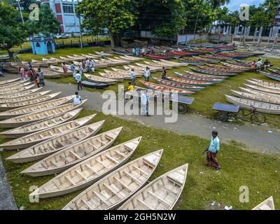 Luftaufnahme von Personen aus Savar und Aminbazar, die am Markt ankommen, um Boote zu kaufen, um sie in ländlichen Gebieten während der Monsunsaison zu benutzen, wenn starker Regen Dörfer und Straßen überflutet, der Preis der Boote ist von BDT 1,500 bis BDT 5,000 (nationale Währung) Je nach Größe und Qualität der verwendeten Materialien. Die Nachfrage nach Dingi und Khosa Nauka (Kleinboot) ist für den Transport von Menschen in hochwassergefährdeten Gebieten gestiegen. Der Markt ist bekannt für den Verkauf von handgefertigten Booten jeden Mittwoch in den letzten 50 Jahren von Juni bis Oktober. Am 5. September 2021 in Manikganj, Bangladesch. (P Stockfoto