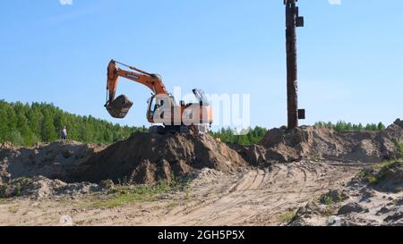 Yellow Excavator Bulldozer Führt Aushub Von Sandgraben Auf Der Baustelle: Moskau, Russland - 30. August 2021. Stockfoto