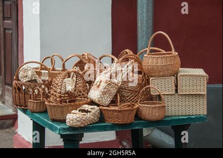 Handgewebte Körbe aus Gras, schöne handgefertigte Produkte in verschiedenen Formen und Größen. Am Straßenrand gestapelte Schilfkörbe. Stockfoto