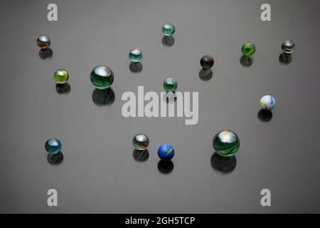 Von oben Hintergrund der Sammlung von dekorativen Glasperlen mit Ornament, die auf der grauen Oberfläche reflektiert Stockfoto