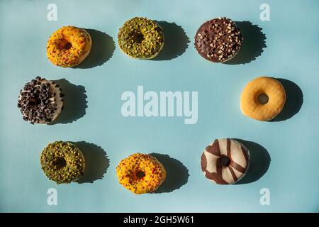 Kreis von Donuts in verschiedenen Farben und Geschmacksrichtungen mit Kopierraum in der Mitte auf blauem Hintergrund Stockfoto