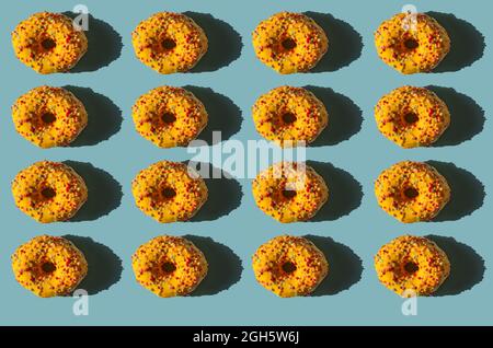 Draufsicht auf viele Donuts mit gelber Abdeckung und farbigen Kugeln auf blauem Hintergrund Stockfoto