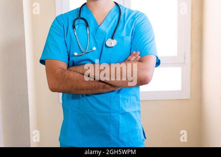 Crop anonyme männliche Medic in blauer Uniform und mit Stethoskop in der Klinik stehen Stockfoto