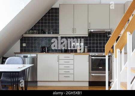 Interieur der modernen Küche mit weißen Möbeln und schwarzen Fliesen an der Wand in minimalem Stil im Haus gestaltet Stockfoto