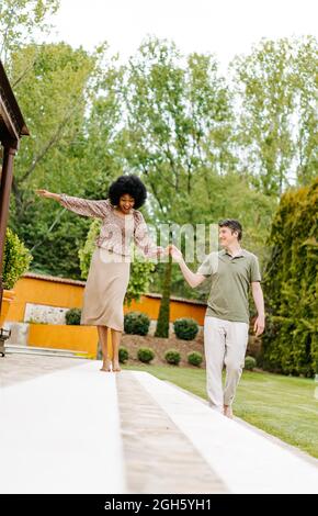 Schwarze Frau, die über Steinstufen der Veranda der Hütte geht und balanciert, während sie die Hand des liebenden Mannes hält Stockfoto
