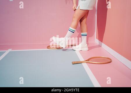 Seitenansicht des Crop unkenntlich stilvolle weibliche Athletin in Kniesocken mit Tennisschläger beim Gehen auf Sportplatz Stockfoto