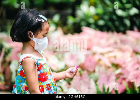 Eine flache Aufnahme mit Fokus auf ein südostasiatisches Mädchen, das eine Gesichtsmask in einem Gartensho trägt Stockfoto