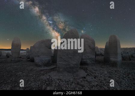 Malerischer Blick auf das spanische Stonehenge auf unwegsamem Gelände unter dem Sonnenuntergangshimmel mit Galaxie in Caceres Spanien Stockfoto