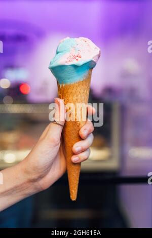 Anonyme junge Hündin mit köstlichem Gelato im Waffelkegel mit unscharfem Hintergrund auf der Straße Stockfoto