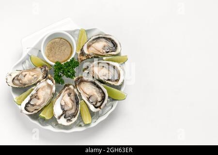 Sechs frische Austern mit Limettenkeilen und Zitrusfrucht-Vinaigrette-Sauce Stockfoto
