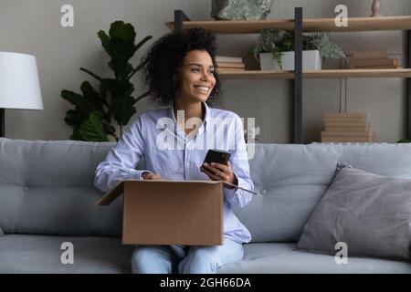 Teen schwarz weiblich blogger planen schießen Paket Auspacken am Telefon Stockfoto