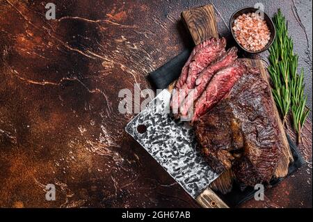 Gebratenes, hängendes, zartes oder in Scheiben geschnittenes Rindersteak auf einem Fleischbrett mit Hackschnitzel. Dunkler Hintergrund. Draufsicht. Speicherplatz kopieren Stockfoto