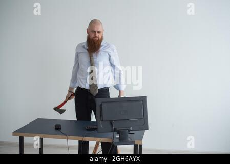 Gestresste verrückte Geschäftsmann zerschlagen seinen Computer im Büro mit Axt Problem Konzept. Der Mann hat Probleme bei der Arbeit und Frustration. Stockfoto