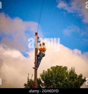 Telefoningenieur, der einen Telegrafenmast hocharbeitet Stockfoto