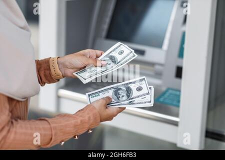 Eine zufriedene Dame hält Geldscheine in den Händen in der Nähe des Geldautomaten. Viel Glück. Geldautomaten Stockfoto