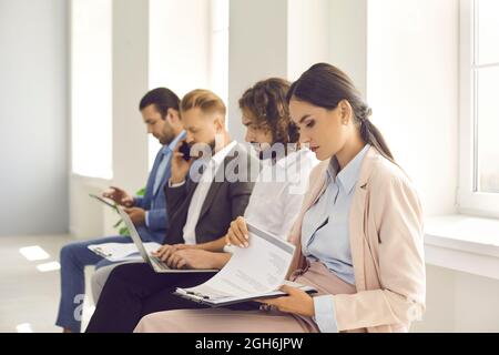 Eine Gruppe junger Menschen, die im Büro sitzen und auf ihr Vorstellungsgespräch warten Stockfoto