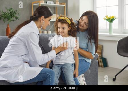 Hausarzt oder Kinderarzt hört dem Atem oder Herzschlag des kleinen Mädchens während des Hausbesuchs zu Stockfoto