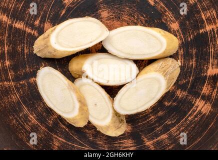 Eine Meerrettichwurzel in Scheiben geschnitten auf einer Tonplatte, Nahaufnahme, Draufsicht. Stockfoto