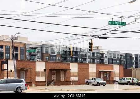 CHARLOTTE, NC, USA-25 JULY 2021: Eine Reihe kleiner Geschäftsbüros mit einem Apartmentkomplex hinter South Tryon in Tremont. Stockfoto