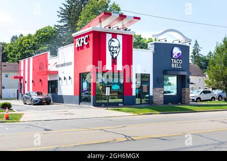 OLEAN, NY, USA-14 AUGUST 2021: Ein KFC und Taco Bell teilen sich ein Gebäude in der Innenstadt. Zeigt den vorderen und seitlichen Drive-Thru des Gebäudes. Stockfoto