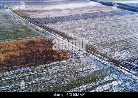 Luftaufnahme von gefrorenen Feldern im Winter von Drohne pov, gepflügte landwirtschaftliche Flächen mit Schnee bedeckt Stockfoto