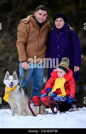 Familie in dritter Generation Großmutter, Sohn und Enkelin im Winterwald, ihr Husky Dog, Schlittenmädchen.neu Stockfoto