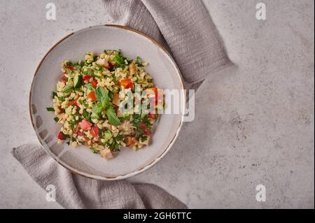 Salat aus Tabbouleh. Traditionelles nahöstliches oder arabisches Gericht mit Petersilie, Minze, Bulgur, Tomaten in einer Schüssel auf Serviette. Draufsicht. Speicherplatz kopieren Stockfoto