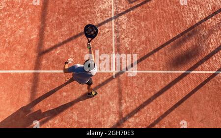 Blick von oben auf einen Mann, der Paddle-Tennis auf einem Platz im Freien spielt. Stockfoto