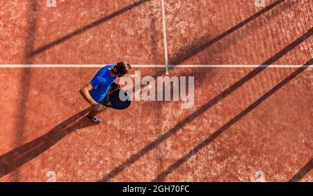 Draufsicht auf einen professionellen Paddle-Tennisspieler, der den Ball auf einem Platz im Freien dribbert. Stockfoto