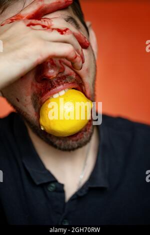 Kreatives Porträt eines Mannes mit einer Zitrone auf rotem Hintergrund Stockfoto