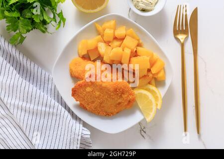 Hausgemachte Hühnerschnitzel mit gebackenen Kartoffeln, Mayonnaise und Zitrone Stockfoto