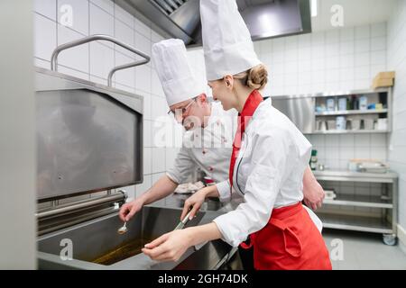 Köche in großen kommerziellen Küche kochen Mahlzeiten zusammen Stockfoto