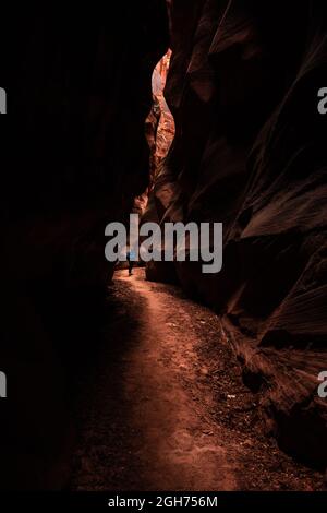 Hiker in Blue Jacket hebt sich von Orange Rock und Shadows ab Stockfoto