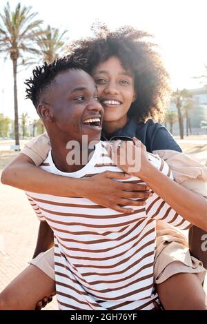 Vertikales Porträt eines jungen afroamerikanischen Paares in der Liebe. Die Freundin huckepack den Freund. Stockfoto