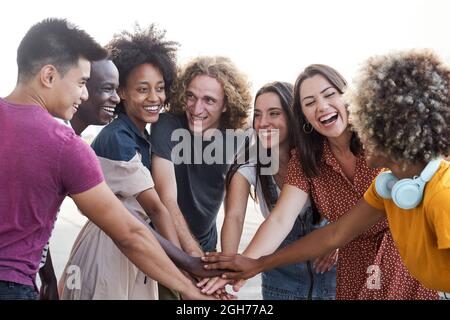 Freunde verschiedener Ethnien stapeln Hand und schauen sich gegenseitig an. Gruppe von Menschen, die Spaß haben und feiern. Konzept von Freundschaft, Glück Stockfoto